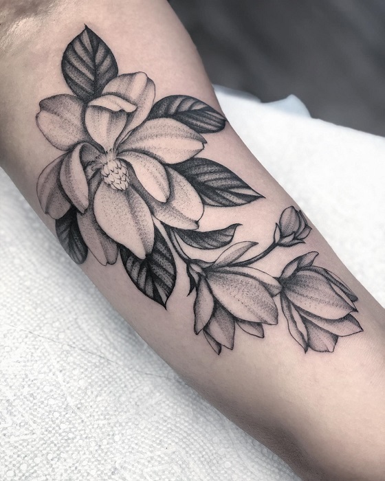 black and grey magnolia forearm tattoo