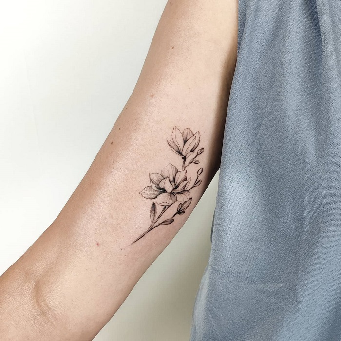 minimalist magnolia inner arm tattoo