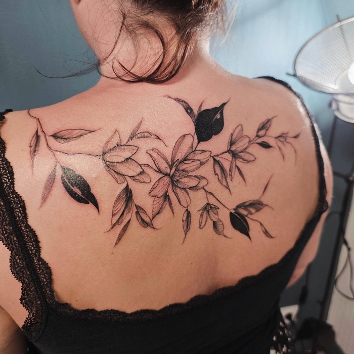 fine line magnolia upper back tattoo