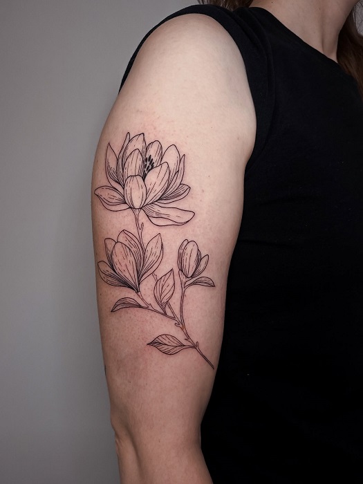 magnolia linework upper arm tattoo
