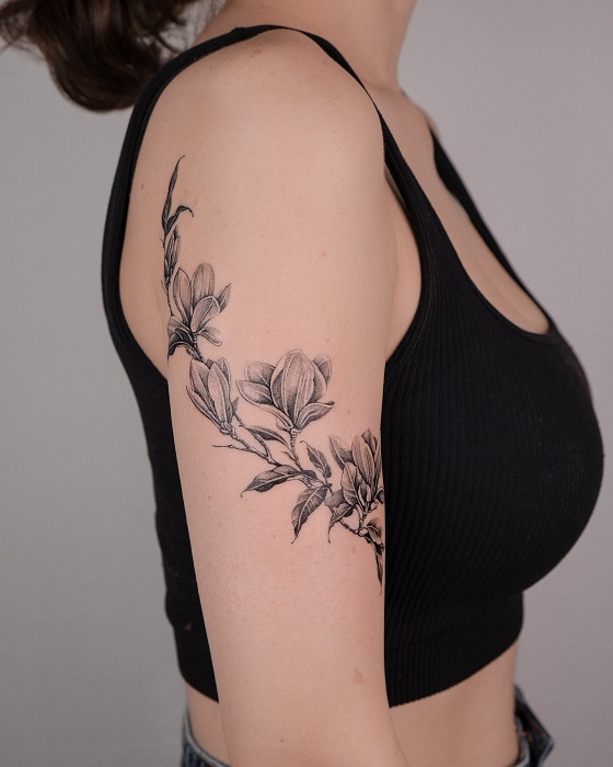 fine line magnolia upper arm tattoo